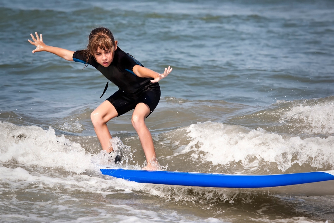 Jente surfer på surfebrett på en bølge i havet.